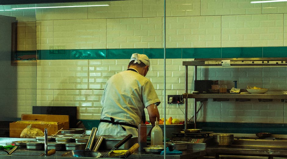 A chef in a commercial kitchen is focused on preparing fresh ingredients for a meal.