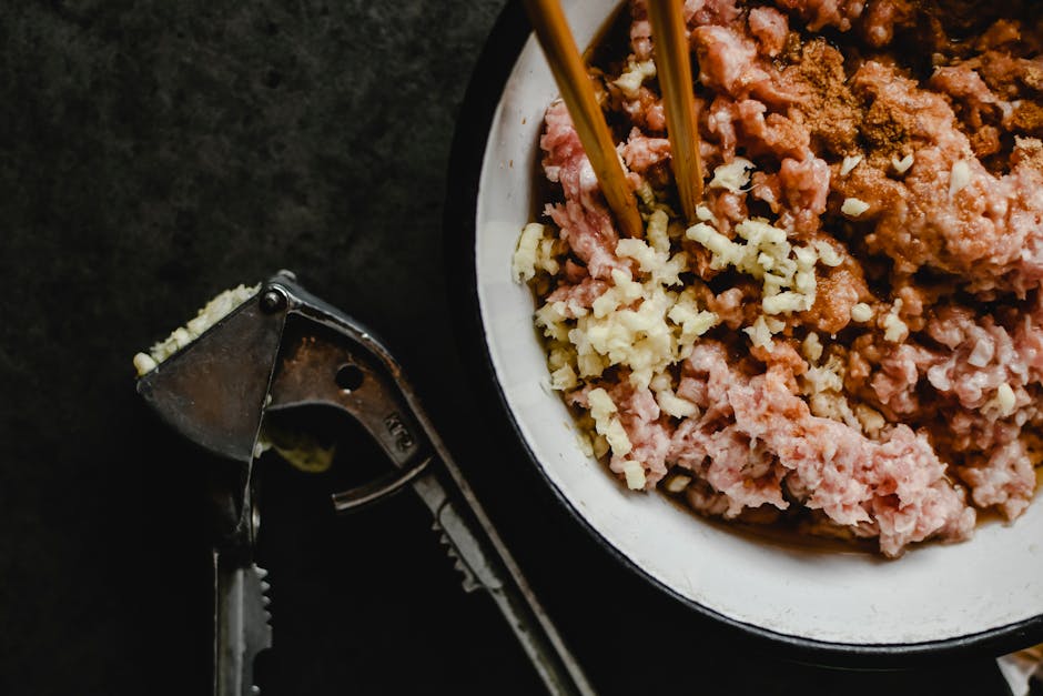 Close-up of raw minced pork, garlic, and spices in a bowl with chopsticks, ready for cooking.