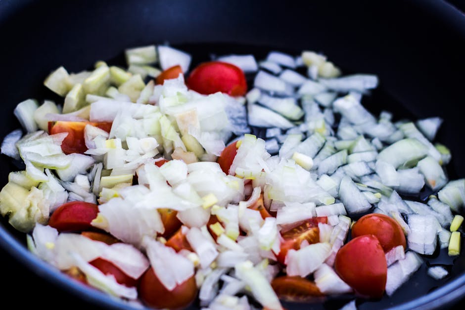 Close-up of chopped onions and cherry tomatoes in a pan, perfect for culinary themes.