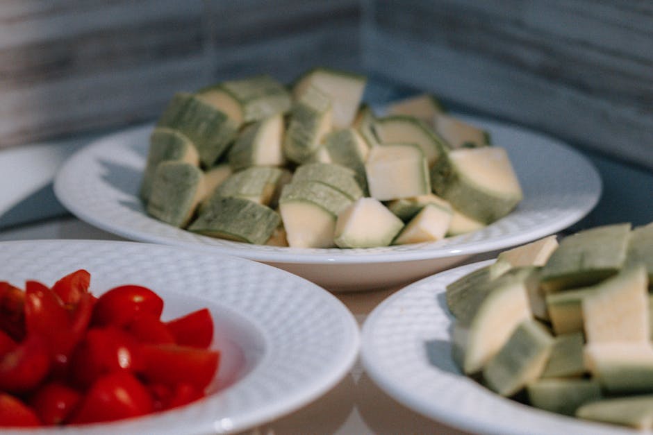 Close-up of sliced vegetables on plates, featuring zucchini and cherry tomatoes.